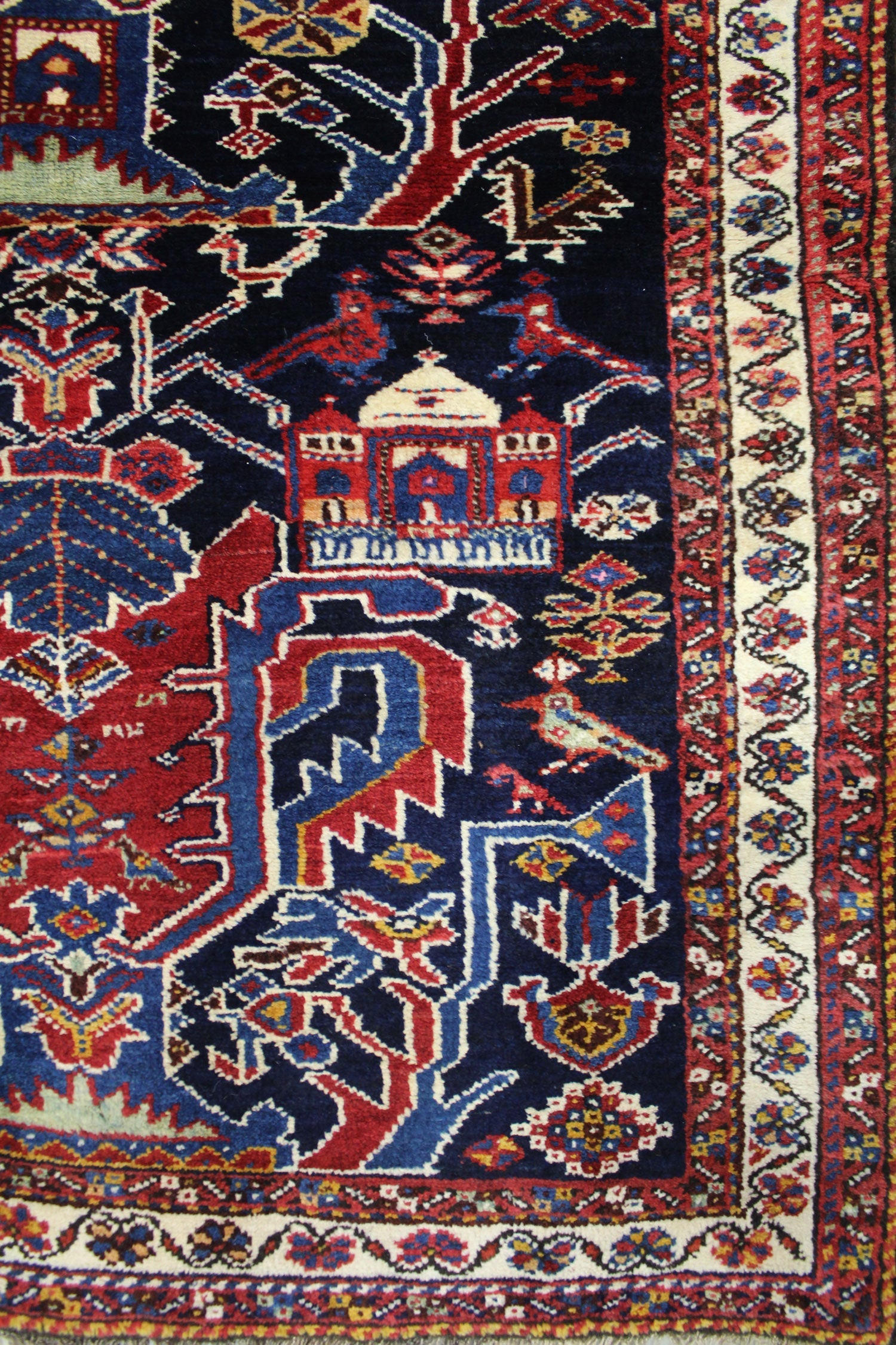 Detail of antique handwoven rug; navy, red, and cream floral and geometric patterns.
