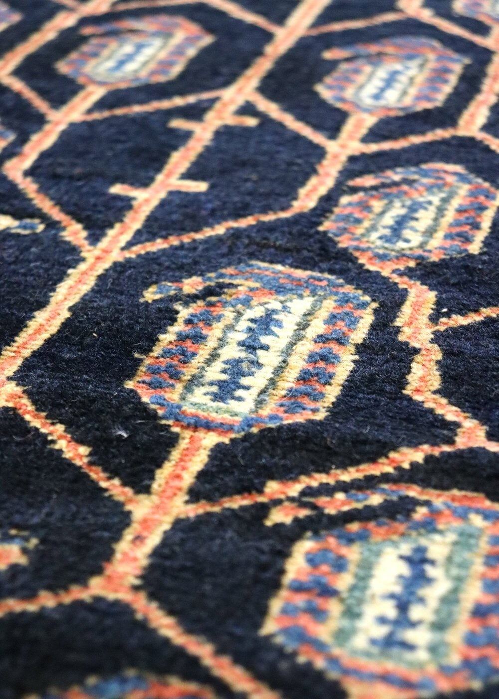 Handwoven rug detail: intricate navy blue tribal pattern with red and beige accents.
