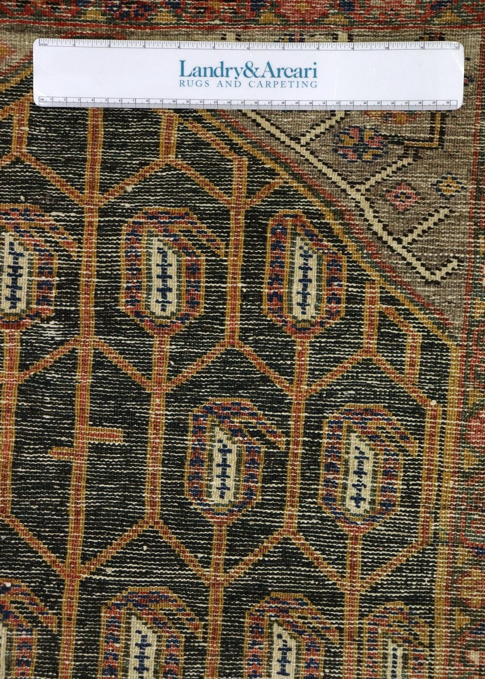 Close-up of antique Malayer rug's handwoven detail, showcasing intricate geometric and floral patterns in muted tones.
