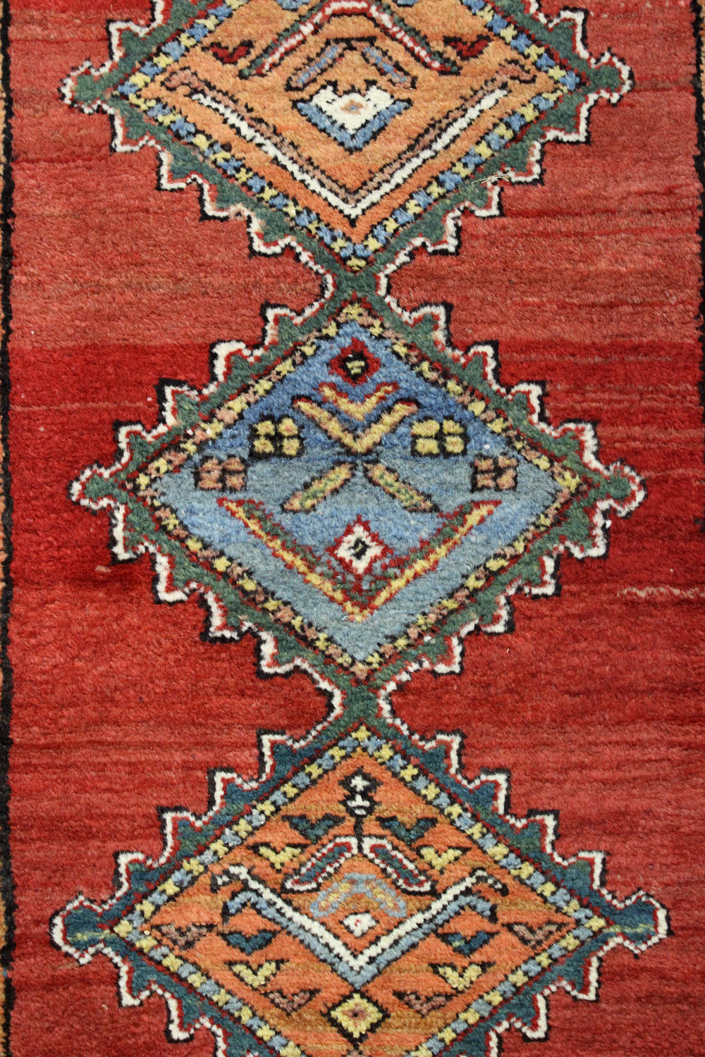 Detail of antique Persian rug, handwoven with red base and colorful geometric patterns.
