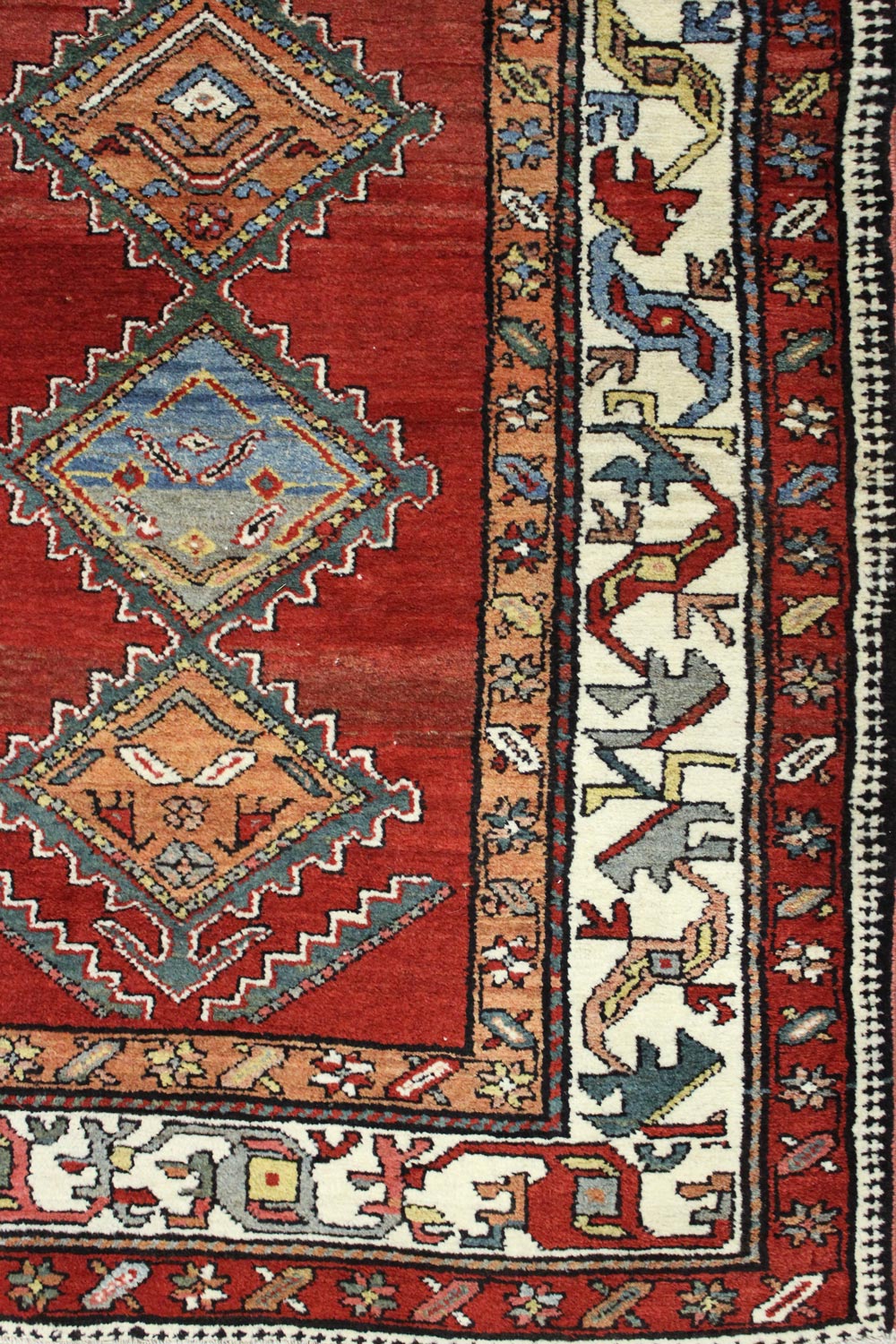 Detail of antique Persian rug, handwoven with intricate red and cream patterns.
